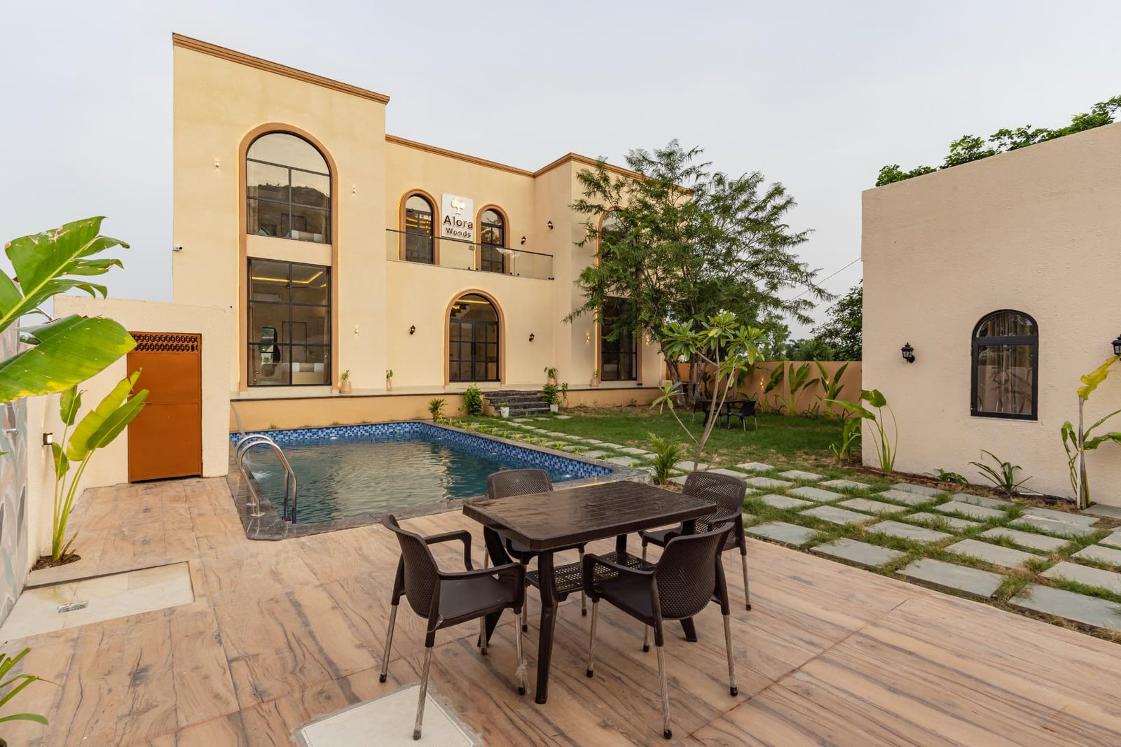 Poolside dining table and chairs on the stone patio at Alora Woods Villa