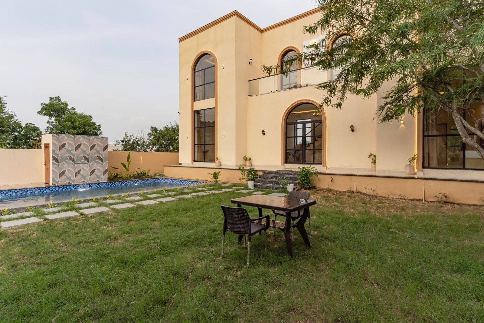 Green lawn with outdoor seating beside the pool at Alora Woods Villa